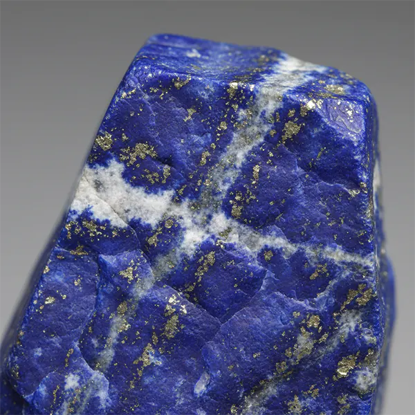 Close-up of natural lapis lazuli stone with golden pyrite and white calcite.